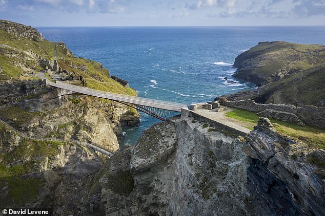 Visitors walk across a footbridge to reach the ruins of Tintagel Castle in Cornwall