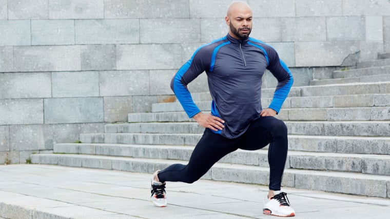 Muscular person outdoors performing walking lunge