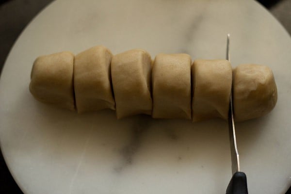 log of dough being cut to portion the dough