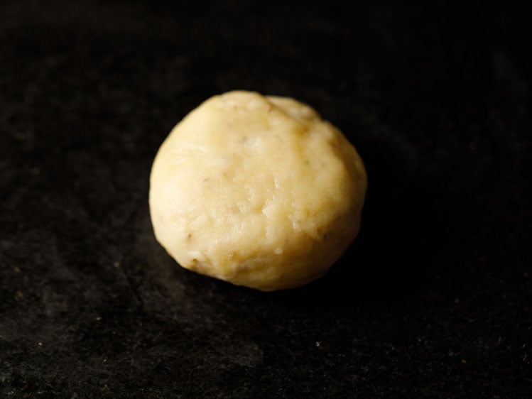 a dough ball flattened on a black surface