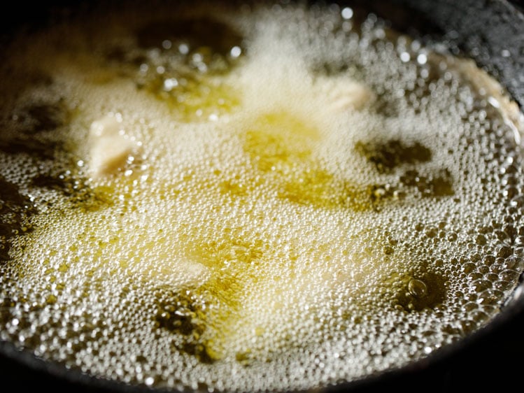 samosa being fried in hot oil in a kadai (wok)