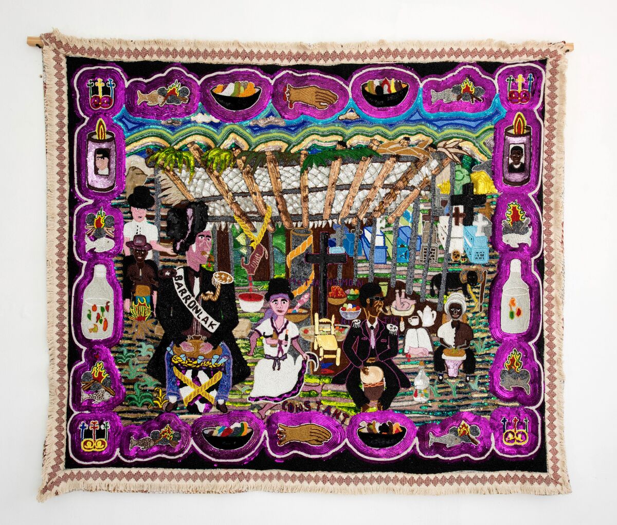 A brilliant tapestry showing a celebratory scene in a village is trimmed in sparkling elements in purple.