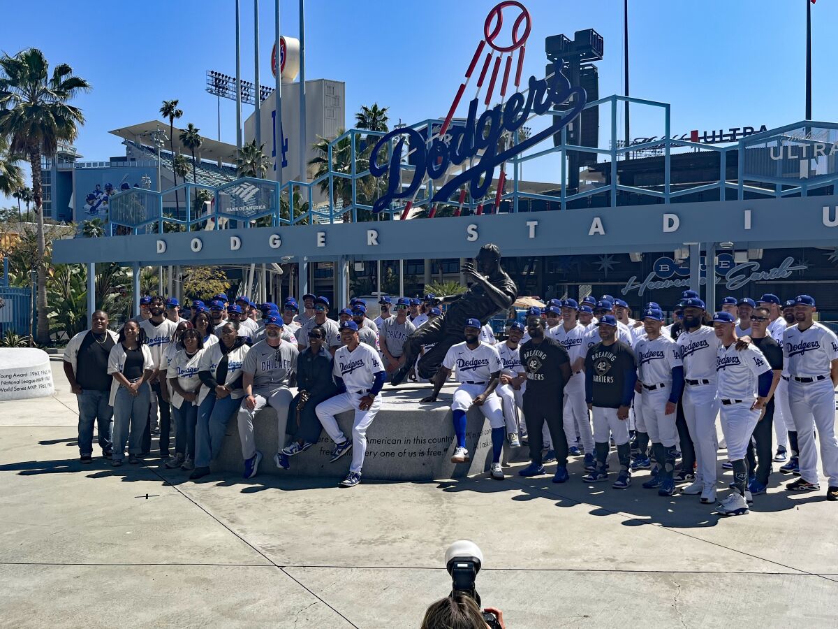 Dodgers and Cubs players pose for photos in front of the Jackie Robinson statue at Dodger Stadium.