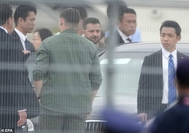 Zelensky is seen through the airport fence as he gets into his motorcade