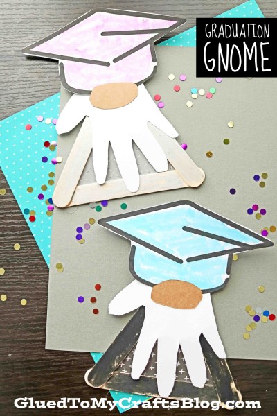Two little gnomes are made from popsicle sticks and a printable. They look like little graduates.