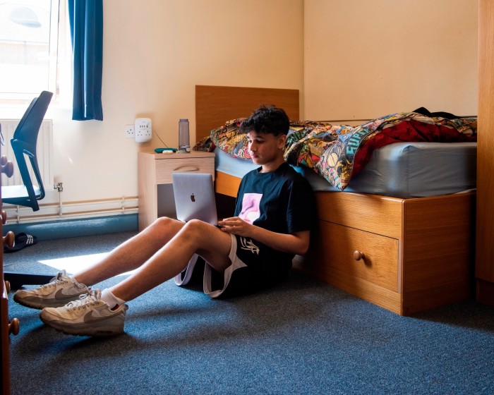 A student sits with his laptop on his lap in student halls of residence 
