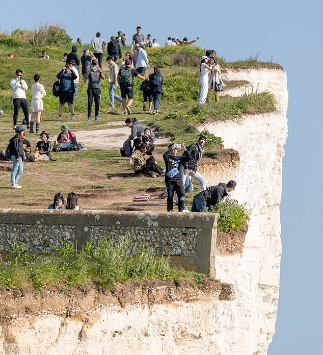 Tourists at Birling Gap, near Beachy Head, East Sussex, were spotted leaning precariously close to the crumbling chalk cliff edge