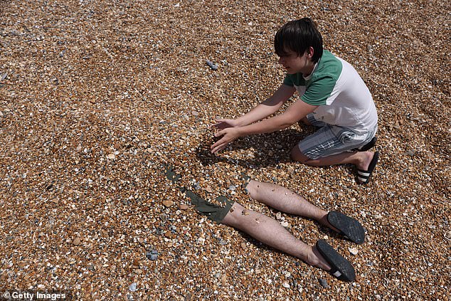 BRIGHTON: A young lad appears to be burying someone alive on the stony beach
