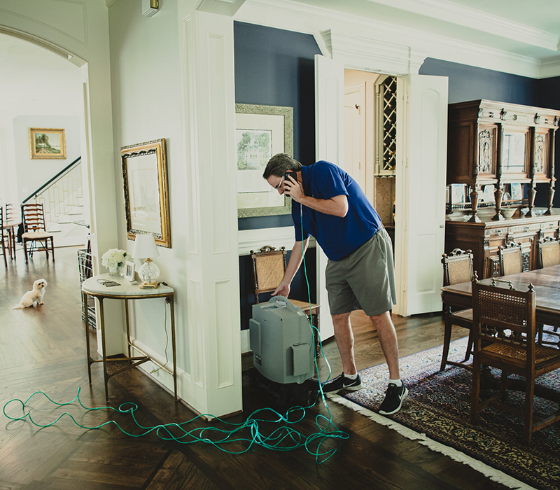 Mr. Kennedy walks over to his home oxygen machine while on a phone call, checking on the suitcase-size machine he is tethered to by a long green oxygen tube.