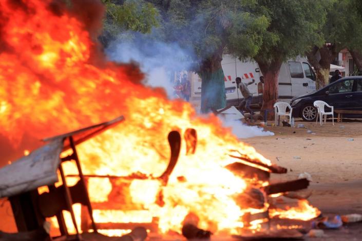 A man throws stones near burning objects during clashes between security forces and supporters of Senegalese opposition leader Ousmane Sonko in Dakar, Senegal - Monday 29 May 2023