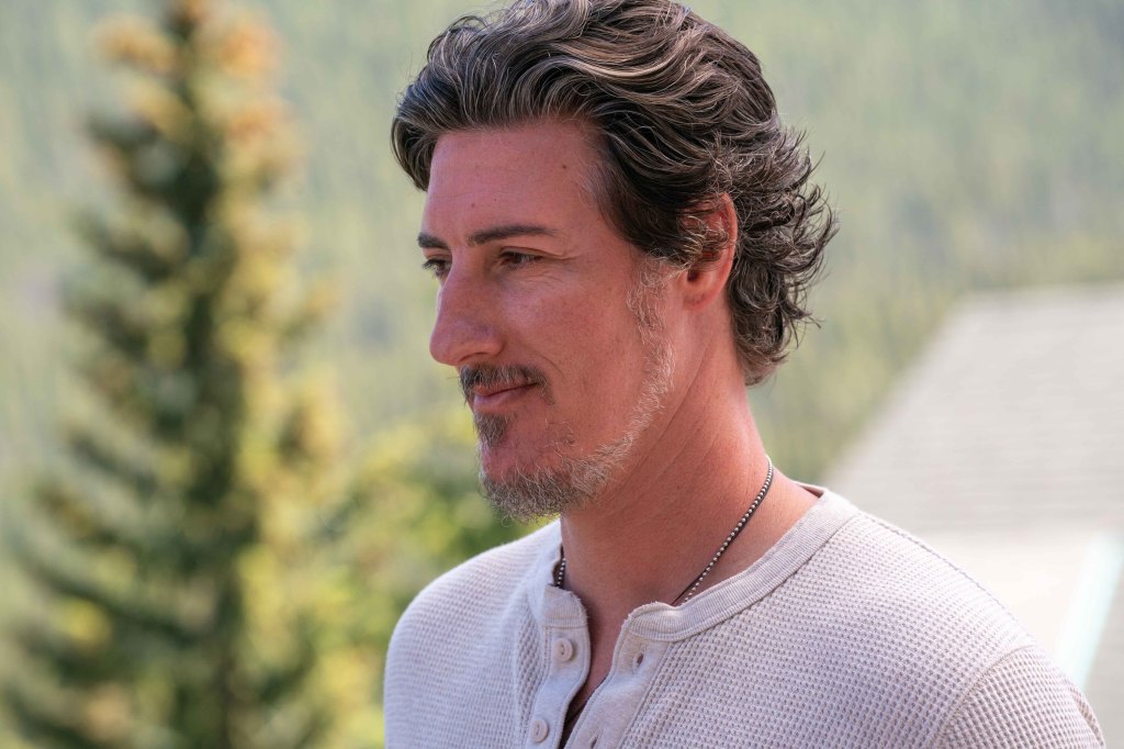 Eric Balfour standing outside by a tree. 