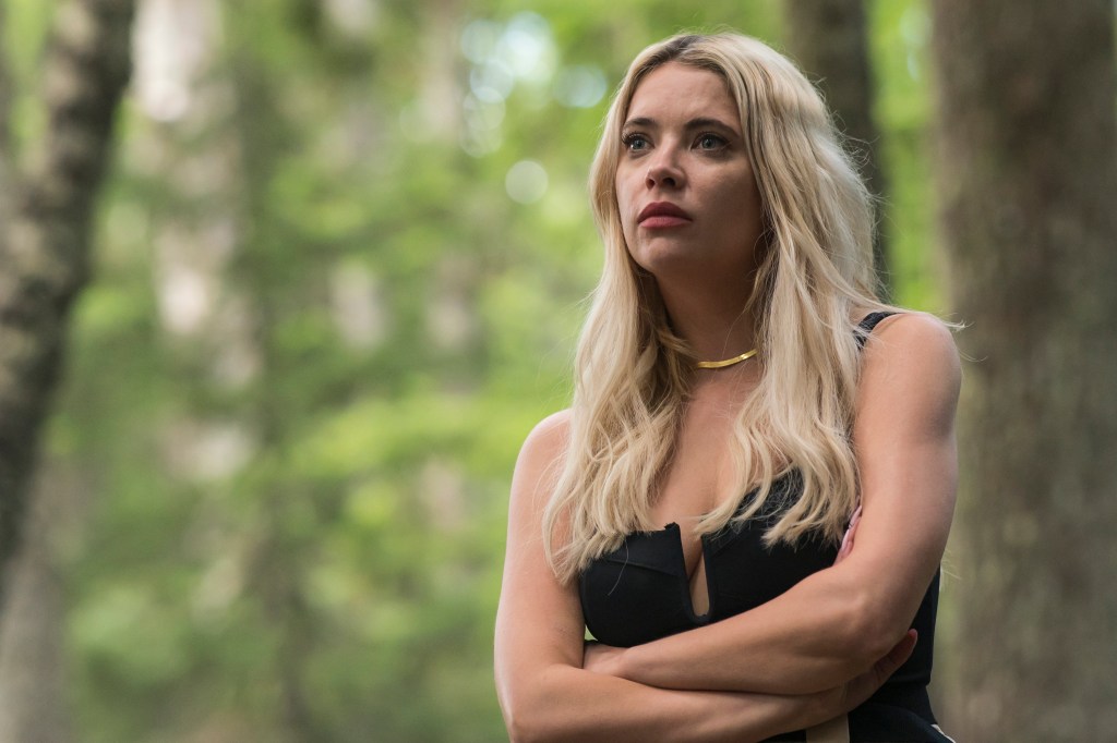Cara (Ashley Benson) standing by a tree looking worried. 