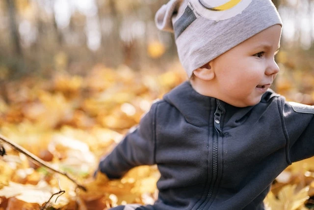 baby playing in fall leaves