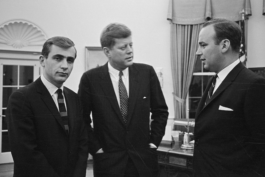 Three men stand in the Oval Office at the White House.