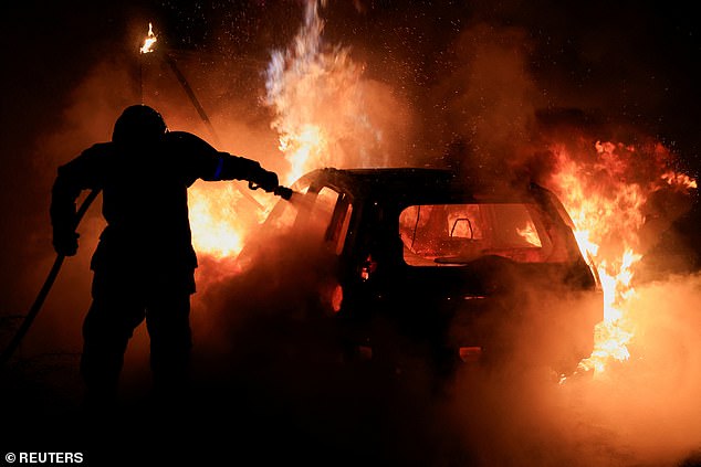 A French firefighter works to extinguish a burning car during the fifth day of protests following the death of Nahel, a 17-year-old teenager killed by a French police officer in Nanterre during a traffic stop, in Tourcoing, France, July 2, 2023