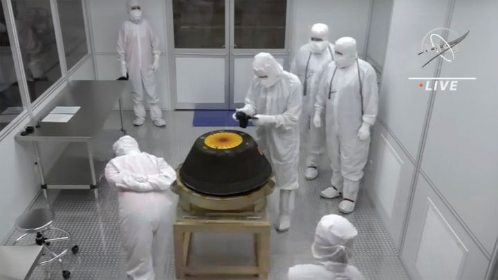 In this image from video provided by NASA, technicians in a clean room examine the sample return capsule from NASA's Osiris-Rex mission after it landed at the Department of Defense's Utah Test and Training Range on Sunday, Sept. 24, 2023. The sample was collected from the asteroid Bennu in October 2020.