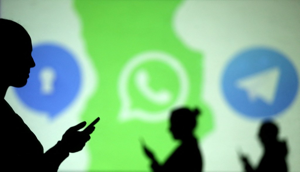 Mobile users are seen next to logos of social media apps Signal, Whatsapp and Telegram 