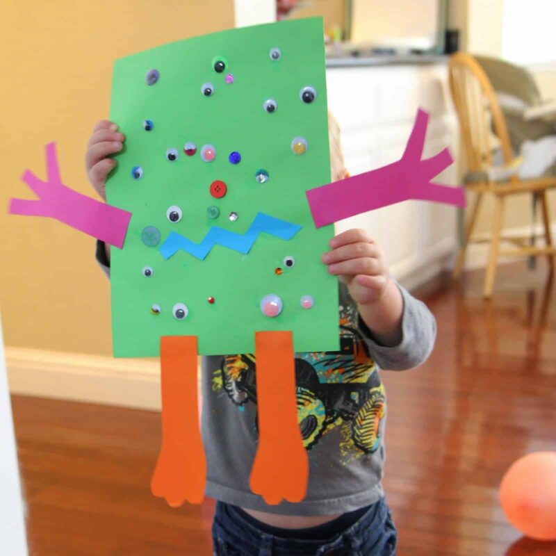 A child is shown holding a construction paper monster.
