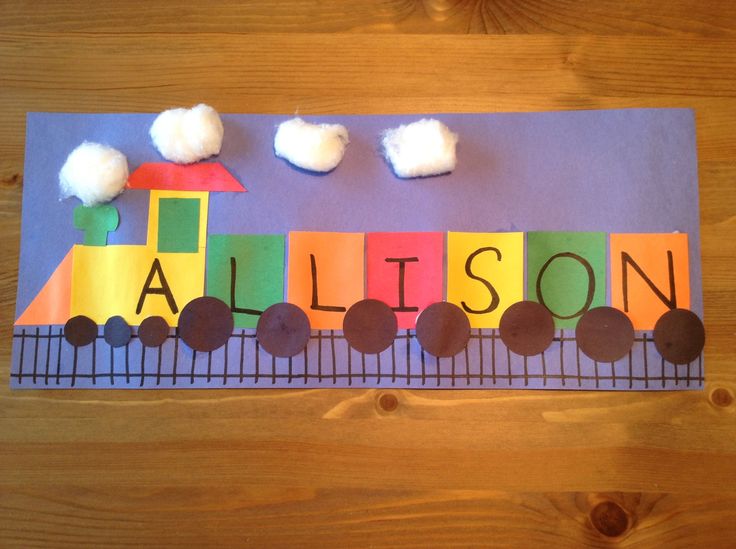 A train is made from primary colored construction paper blocks on a blue background. The body of the train spells the name Allison.