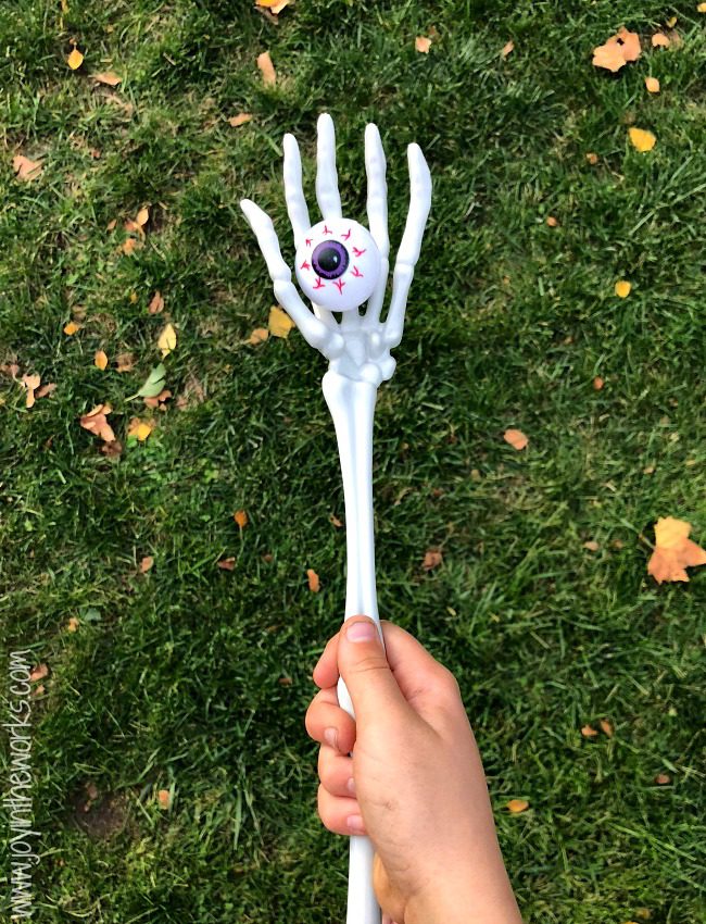 A child's hand is shown carrying a skeleton arm that has a fake eyeball in the hand portion (Halloween Activities)