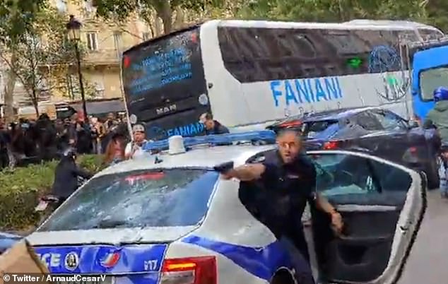 The shocking moment a police officer raises a pistol at protestors during a demo in Paris