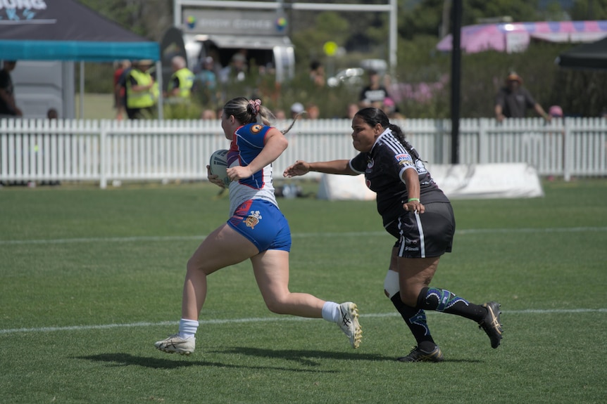 two women on opposing teams playing rugby league