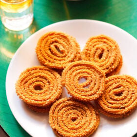 chakli served in a circle with a center chakli on a white plate with a green background