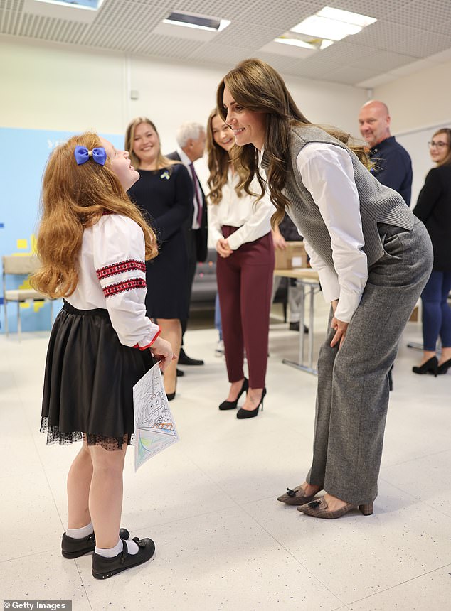 Princess Kate chatted to a sweet schoolgirl who wore a blue and yellow bow in her hair and had a painting for the royal