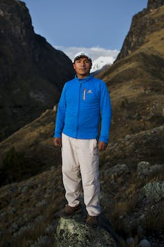Peruvian man standing amid mountains.