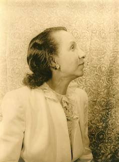 An old sepia photo of a woman facing the right hand side of the image and looking upwards.