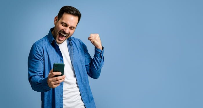 Investor with cellphone celebrating.