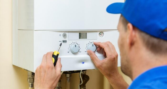 A worker setting up central gas heating boiler in a home