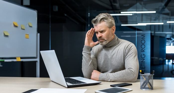 A frustrated man looking at a computer screen.