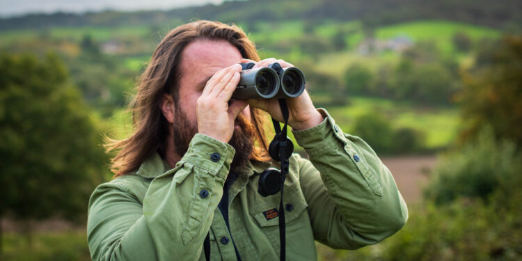 Expert holds one of the best binoculars while in nature, observing.