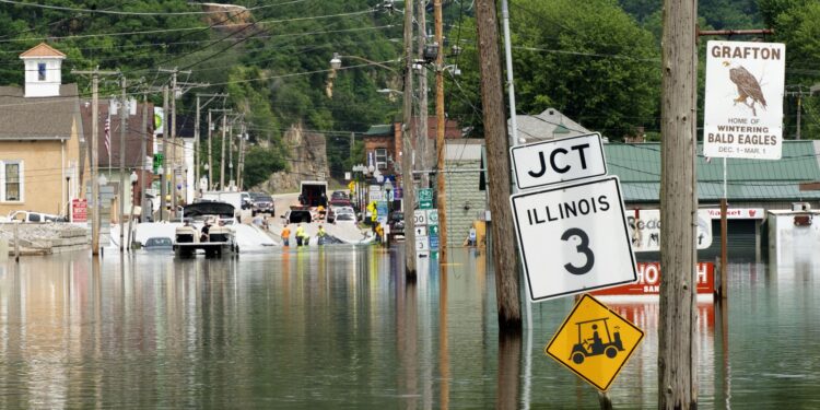 A sign that says Illinois 3 jct on a small town street is surrounded by flood waters