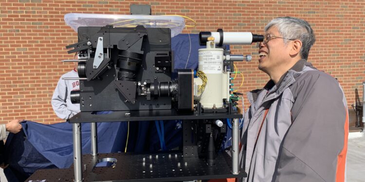 an engineer looks into an eyepiece connected to a large lidar instrument.