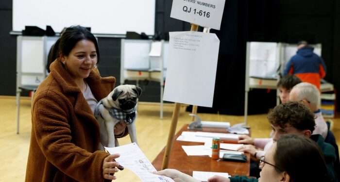 A woman holds a dog as she votes at a polling station during Ireland’s general election in Dublin on Friday