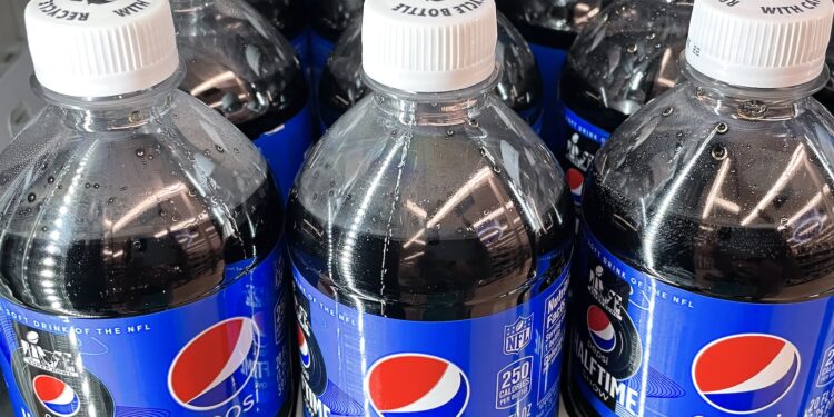 Three plastic bottles of Pepsi on a store shelf, side by side.