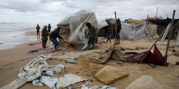 © Reuters. Displaced Palestinians inspect a damaged tent following rising sea levels and heavy rainfall, amid the ongoing conflict between Israel and Hamas, in Khan Younis in the southern Gaza Strip, November 25, 2024. REUTERS/Hatem Khaled