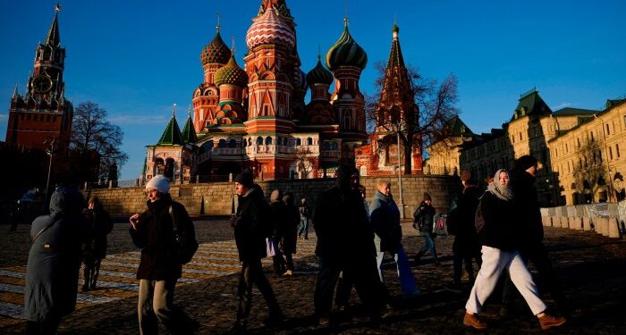 People walk on the Red square next to St Basil’s Cathedral and the Spasskaya tower of the Kremlin