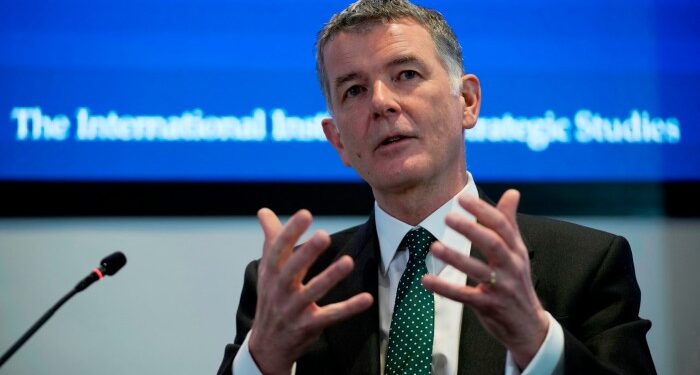 Richard Moore is seen speaking and gesturing with his hands at the International Institute for Strategic Studies in London.