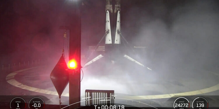 A black and white spacex falcon 9 rocket first stage sits on the deck of a ship at sea.