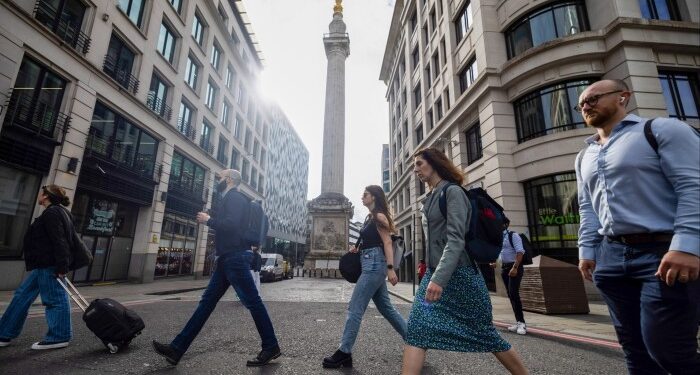 Commuters pass The Monument to the great fire of London