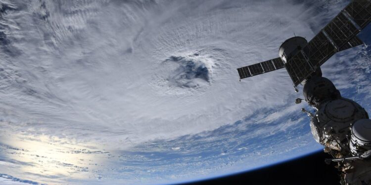 a hurricane seen from space, with a space station vehicle hanging in frame.