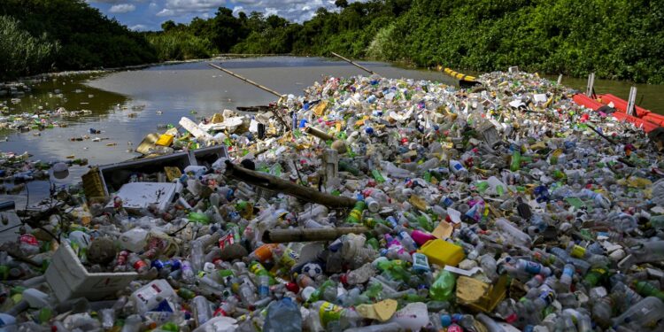 Plastic pollution clogging a river, with trees in background