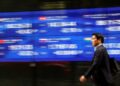 © Reuters. FILE PHOTO: A passerby walks past an electric monitor displaying various countries' stock price index outside a bank in Tokyo, Japan, March 22, 2023. REUTERS/Issei Kato/File Photo