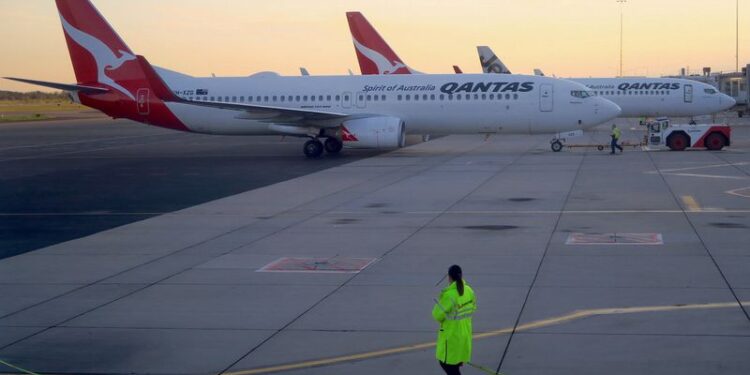 © Reuters. FILE PHOTO: Workers can be seen near Qantas Airways, Australia's national carrier, Boeing 737-800 aircraft on the tarmac at Adelaide Airport, Australia, August 22, 2018. REUTERS/David Gray/File Photo