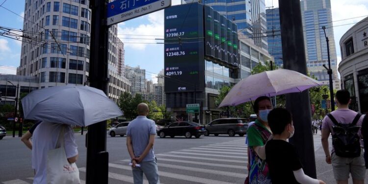 © Reuters. FILE PHOTO: Pedestrians wait to cross a road at a junction near a giant display of stock indexes in Shanghai, China August 3, 2022. REUTERS/Aly Song/File Photo