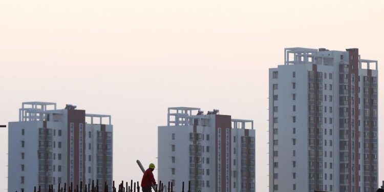 © Reuters. FILE PHOTO: A worker stands on the scaffolding at a construction site against a backdrop of residential buildings in Huaian, Jiangsu province, China October 18, 2018. Picture taken October 18, 2018.  REUTERS/Stringer/File Photo