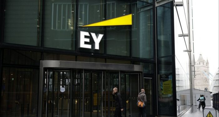 Pedestrians walk past the EY office in London